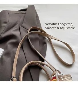 Detail of beige woven bucket bag with adjustable leather strap and pearl bead charm