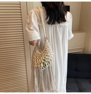 Close-up of white woven hollow handbag with long tassels and green inner bag