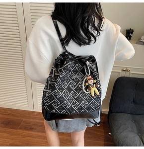 Detail of geometric pattern tote bag with decorative cartoon pendant and black leather base