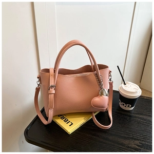Pink litchi texture crossbody bag detail with heart charm and round top handle