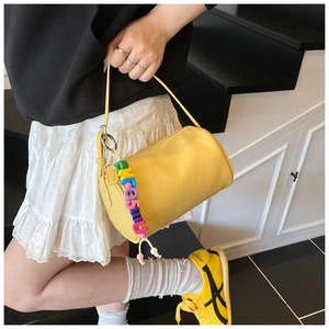 Detailed shot of yellow litchi pattern cylinder bag with a colorful beaded strap