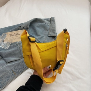 Detail of bright yellow nylon crossbody bag with woven strap and industrial buckle
