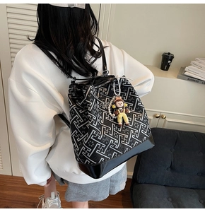 Detail shot of geometric patterned tote bag with glossy leather base and cute doll pendant