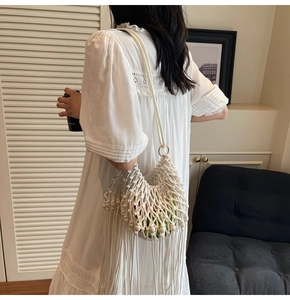 Detail of white woven bohemian shoulder bag with long tassels and decorative wooden beads