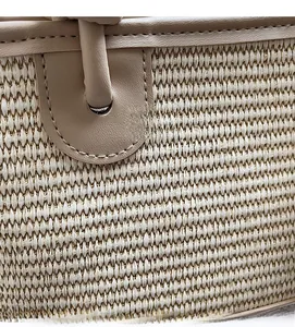 Detail of woven straw texture and beige leather stitching on a stylish bucket bag