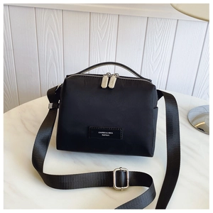 Détail du sac bandoulière en nylon noir avec logo et fermetures éclair argentées