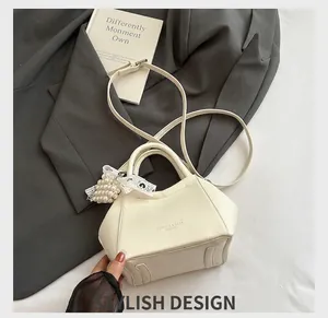 Mini borsa a secchiello in pelle crema con ciondolo a fiocco in pizzo e tracolla