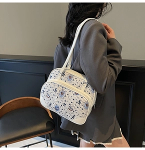 Detail of off-white quilted shoulder bag with bear prints worn with dark grey blazer
