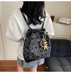 Detail of a chic black backpack with geometric patterns and a cartoon pendant on a shoulder strap