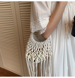 Detail of white macrame bag featuring wooden beads, woven mesh and long fringe tassels