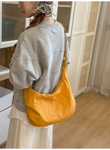 Detailed view of yellow crescent nylon bag featuring adjustable strap and heart embroidery