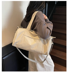 Detail of cream travel tote showing side pocket and adjustable shoulder strap