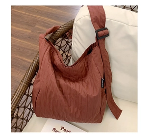 Dettaglio della trama plissettata e dell'etichetta sulla borsa hobo in tessuto rosso mattone