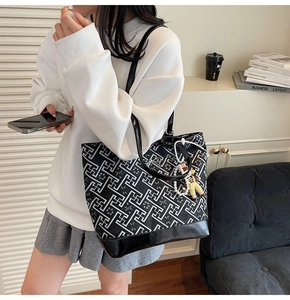 Detail of a large tote bag with black and white geometric pattern and pearl doll charm