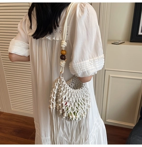 Close-up of bohemian white woven bag featuring tassel fringe and wooden bead shoulder strap