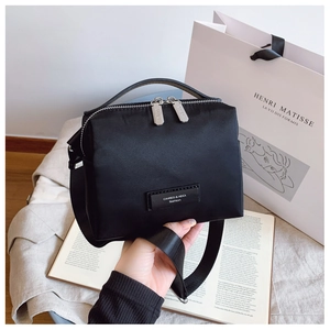Détail du sac bandoulière en nylon noir avec zip argenté et bandoulière tissée