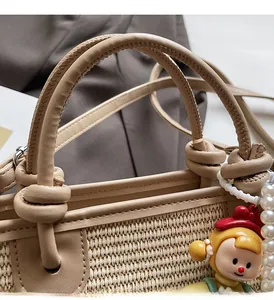 Close-up of woven straw bucket bag with PU leather handle and pearl charm detail