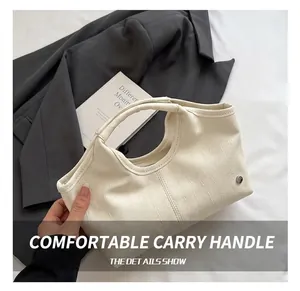 Detail of integrated comfortable handle on cream pebble leather tote bag with fine stitching