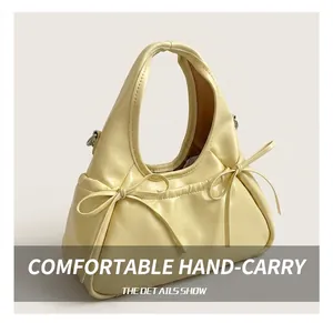 Detail of cream yellow bag featuring soft handle, bow tie, and precision stitching detail