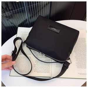 Détail d'un petit sac bandoulière en nylon noir avec double fermeture éclair sur magazine