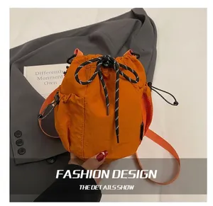 Detail view of the orange nylon drawstring bucket bag with textured fabric and mesh pocket