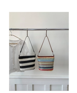 Detailed view of woven shoulder bag with bold stripes and fine faux leather straps