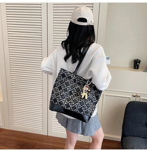 Detail of a large checkered tote bag with a cute charm shown on a female model