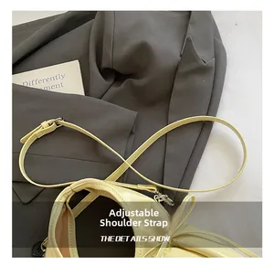 Detail of adjustable shoulder strap on a light yellow leather pillow bag for women