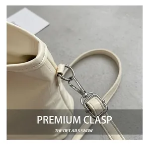 Detailed close-up of metal hook and crocodile embossed leather on cream white bucket bag