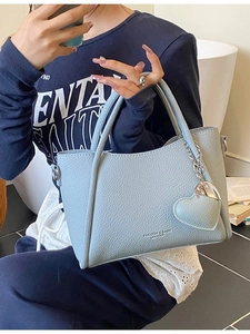 Sky blue litchi pattern leather handbag with heart pendant shown in lifestyle setting