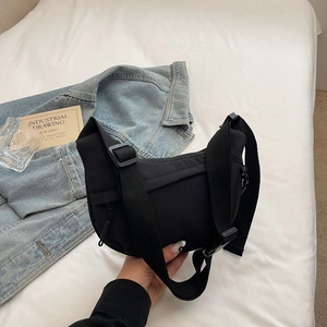Close-up of minimalist black nylon crescent bag featuring wide strap and sturdy zipper