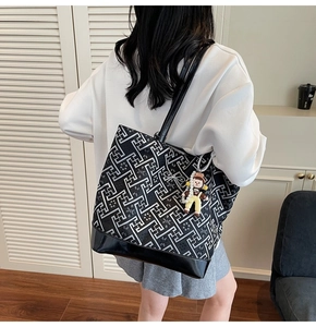 Macro shot of geometric pattern tote bag featuring a cute cartoon doll charm