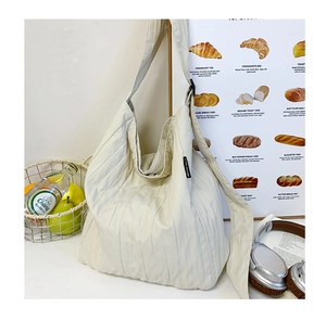 Dettaglio macro della borsa tote beige a pieghe con cuciture verticali e tracolla larga