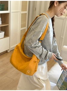 Detail of ginger yellow dumpling bag with heart embroidery and adjustable strap on model