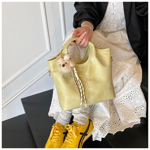 Detail of yellow crocodile pattern leather handbag with cute plush bear charm accessory