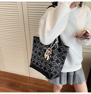 Detail of embroidered tote bag with geometric patterns and leather bottom on model