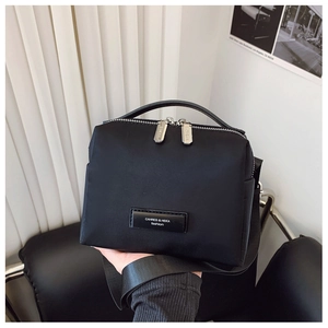 Détails du sac bandoulière en nylon noir avec zips argentés et bandoulière réglable