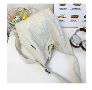 Dettaglio della borsa tote in tela beige plissettata con trama del tessuto e tracolla