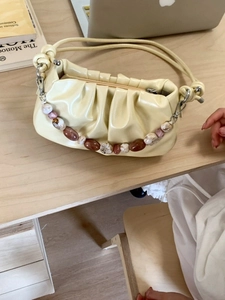 Pale yellow pleated cloud bag with beaded chain on a desk for office lifestyle