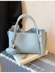 Sky blue litchi leather handbag with heart pendant and shoulder strap on luggage