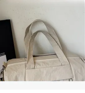 Detailed close-up of reinforced handles and metal zipper on beige travel fitness bag
