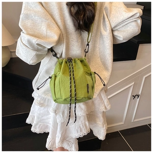 Detail of green nylon drawstring bucket bag with mesh side pocket and adjustable strap