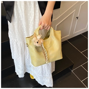 Detail of light green bucket bag with crocodile texture and cute plush bear charm