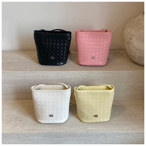 Detail view of woven bucket bags in black, pink, white, and yellow leather with thin straps