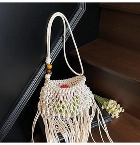 Detail of woven macrame shoulder bag featuring fringe tassel and decorative wooden beads