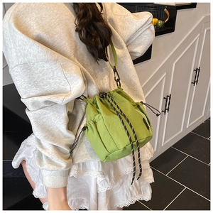 Detail of green nylon drawstring bucket bag with mesh pocket and striped cord strap