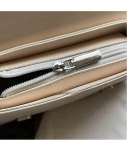 Close-up of smooth silver zipper and stitching on the cream leather small square bag
