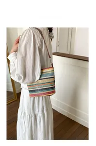 Close-up of colorful striped crochet tote bag with brown leather strap on white dress
