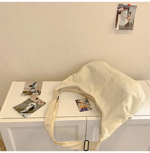 Detailed view of cream canvas crescent bag showing silver metal zipper and durable texture