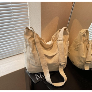 Detail view of cream canvas messenger bag with adjustable strap and textured side pocket